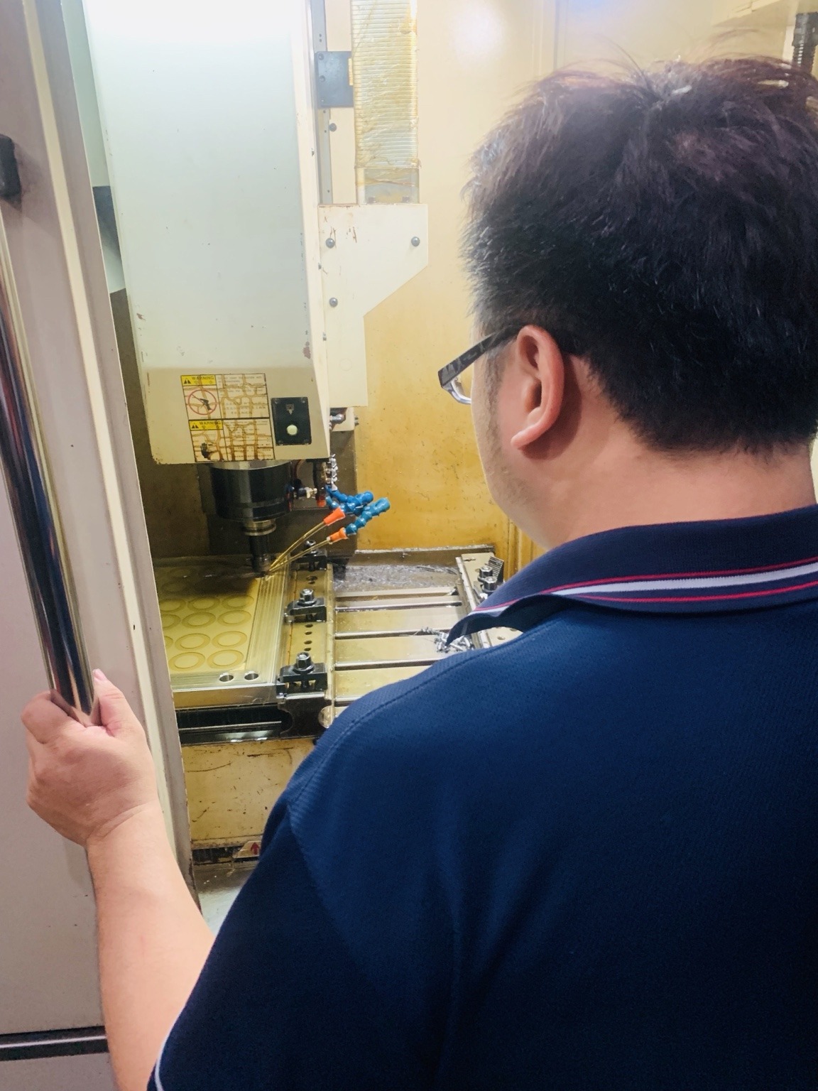 人員於 CNC 銑床前查看模具加工